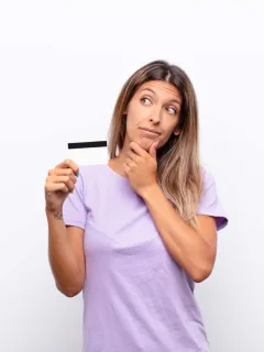 Woman holding a Secured Credit Card and thinking.