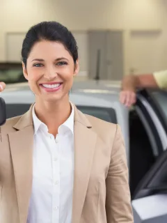 Happy woman holding her car keys after a Bank of America Auto Loan.