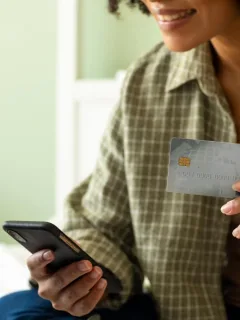 Woman holding a reward credit cards and using a computer.