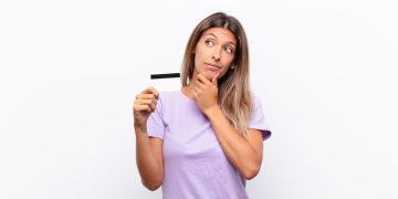 Woman holding a Secured Credit Card and thinking.