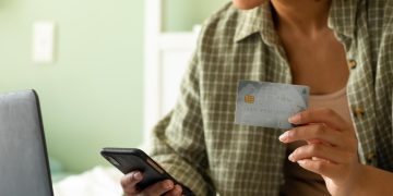 Woman holding a reward credit cards and using a computer.