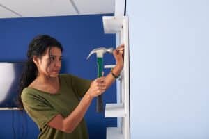 Woman using hammer and home repair costs